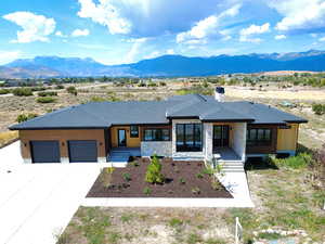 Prairie-style house with an attached garage, driveway, a mountain view, and a chimney