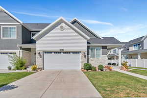 View of front of property with stone siding, driveway, roof with shingles, and a garage
