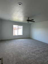Carpeted empty room with a textured ceiling and baseboards