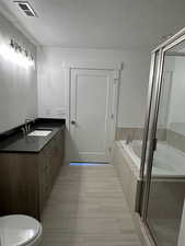 Full bath featuring vanity, a shower stall, a bath, and a textured ceiling