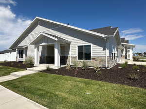 View of front of home featuring stone siding, a front lawn, and board and batten siding