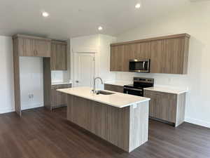 Kitchen featuring stainless steel appliances, modern cabinets, recessed lighting, an island with sink, and dark wood-style flooring