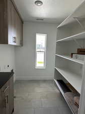 Laundry room featuring hookup for an electric dryer, cabinet space, a textured ceiling, and washer hookup