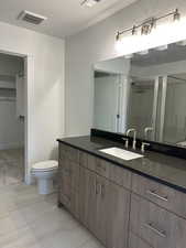 Full bath with a shower stall, a textured ceiling, vanity, and a spacious closet