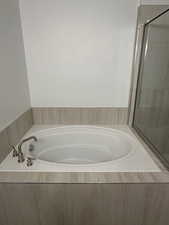 Bathroom featuring a bath and a tile shower