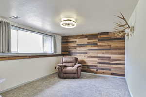 Sitting room with wood walls, carpet floors, and a textured ceiling
