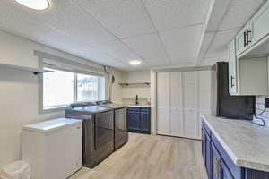 Laundry area with light wood finished floors, washing machine and dryer, and cabinet space