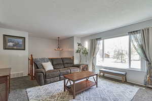 Carpeted living area with a textured ceiling and baseboards