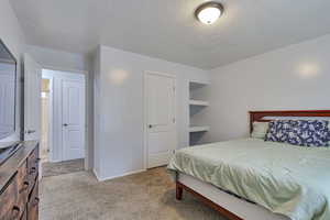Bedroom with light carpet and a textured ceiling