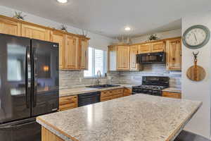 Kitchen with black appliances, backsplash, a kitchen island, light countertops, and recessed lighting