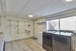 Laundry area with light wood-style flooring and washer and clothes dryer