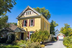 Victorian-style house with a garage, brick siding, an outdoor structure, and driveway
