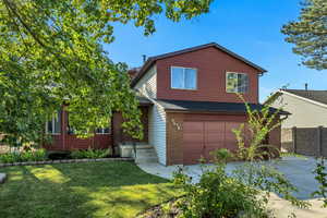 View of front of house with an attached garage, a shingled roof, brick siding, a front lawn, and driveway