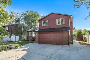 View of front of house with a garage, concrete driveway, brick siding, a shingled roof, and a gate