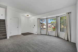 Spare room with stairway, carpet floors, and plenty of natural light