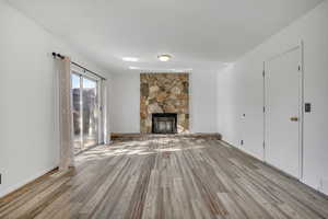 Unfurnished living room featuring a stone fireplace and wood finished floors