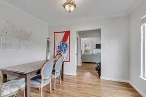 Unit A dining area featuring light wood-style floors and crown molding.