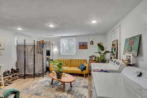Unit B Living room featuring wood finished floors, washer and dryer, a textured ceiling, and recessed lighting.