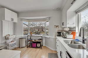 Unit A kitchen featuring white cabinetry, light wood finished floors, light stone countertops, and decorative backsplash.