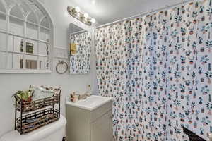 Unit B full bath with vanity, a shower with curtain, and a textured ceiling.
