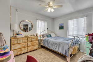 Unit A bedroom featuring light colored carpet and a ceiling fan.