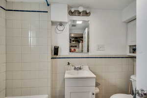 Unit C bathroom with tile walls, vanity, water heater, and wainscoting.