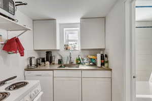 Unit C kitchen with white cabinetry, light countertops, tasteful backsplash, and white appliances.