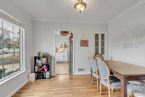 Unit A dining space featuring light wood-style flooring and crown molding.