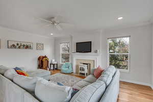 Unit A living room featuring ornamental molding, light wood finished floors, recessed lighting, and a ceiling fan.