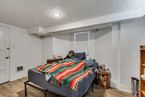 Unit C bedroom with a textured ceiling and light lvp floors.