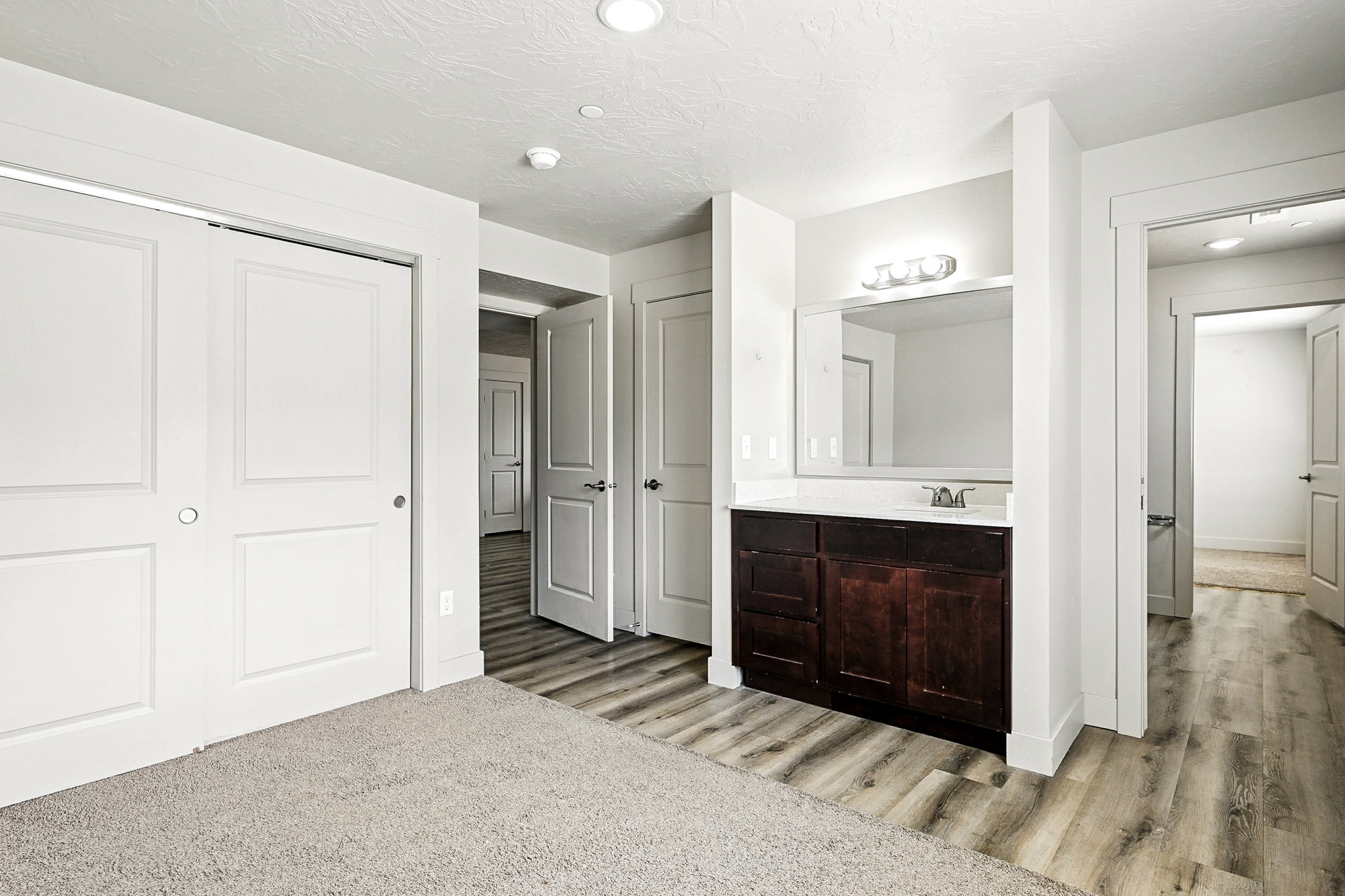 Unfurnished bedroom featuring a textured ceiling, light wood-style flooring, connected bathroom, a closet, and recessed lighting