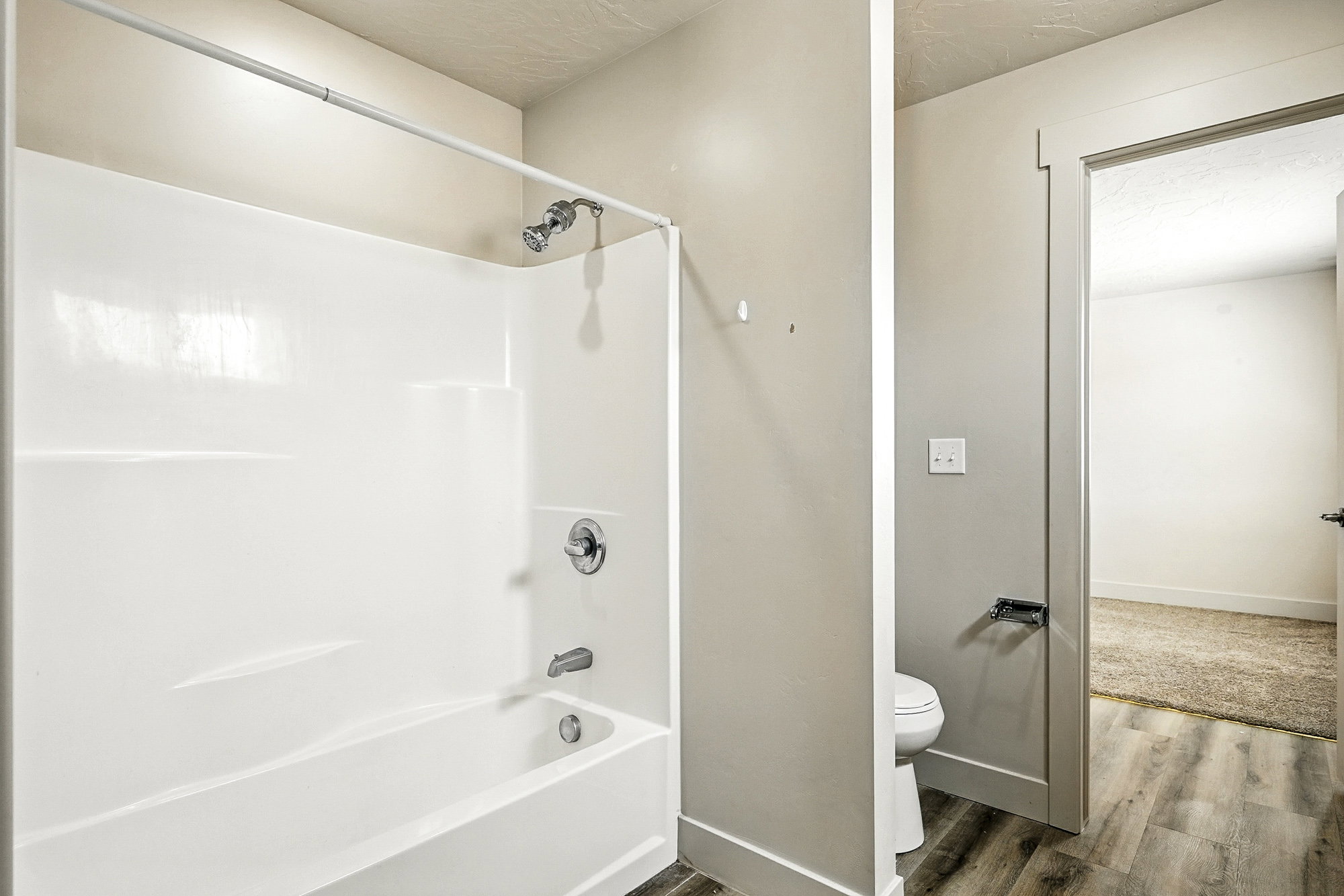 Full bathroom featuring bathing tub / shower combination, wood finished floors, and a textured ceiling