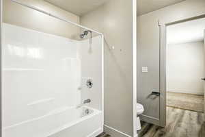 Full bathroom featuring bathing tub / shower combination, wood finished floors, and a textured ceiling