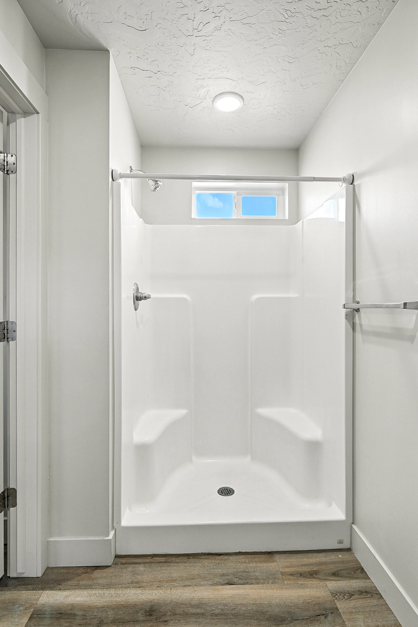Full bathroom featuring a shower stall, wood finished floors, and a textured ceiling