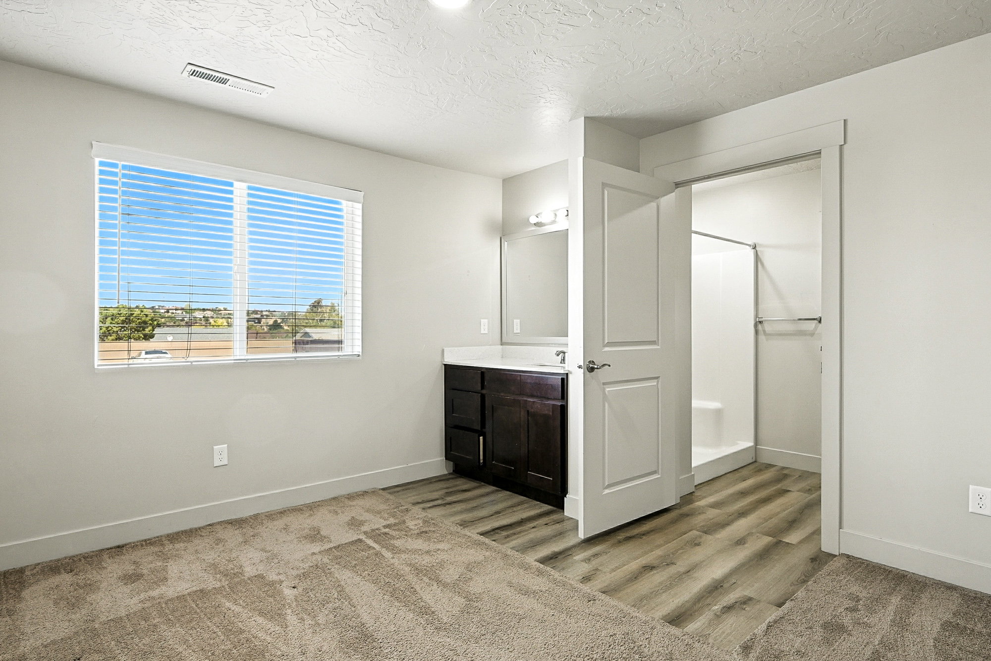 Bathroom featuring a shower stall, vanity, a textured ceiling, and light wood finished floors