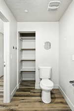 Bathroom with dark wood-type flooring, a textured ceiling, and recessed lighting