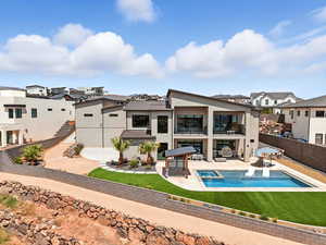 Rear view of property featuring a fenced backyard, a patio, a balcony, a residential view, and a pool with connected hot tub
