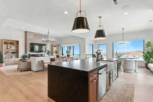 Kitchen featuring a chandelier, open floor plan, a center island with sink, and recessed lighting