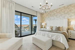 Bedroom with wallpapered walls, carpet, access to outside, and a chandelier