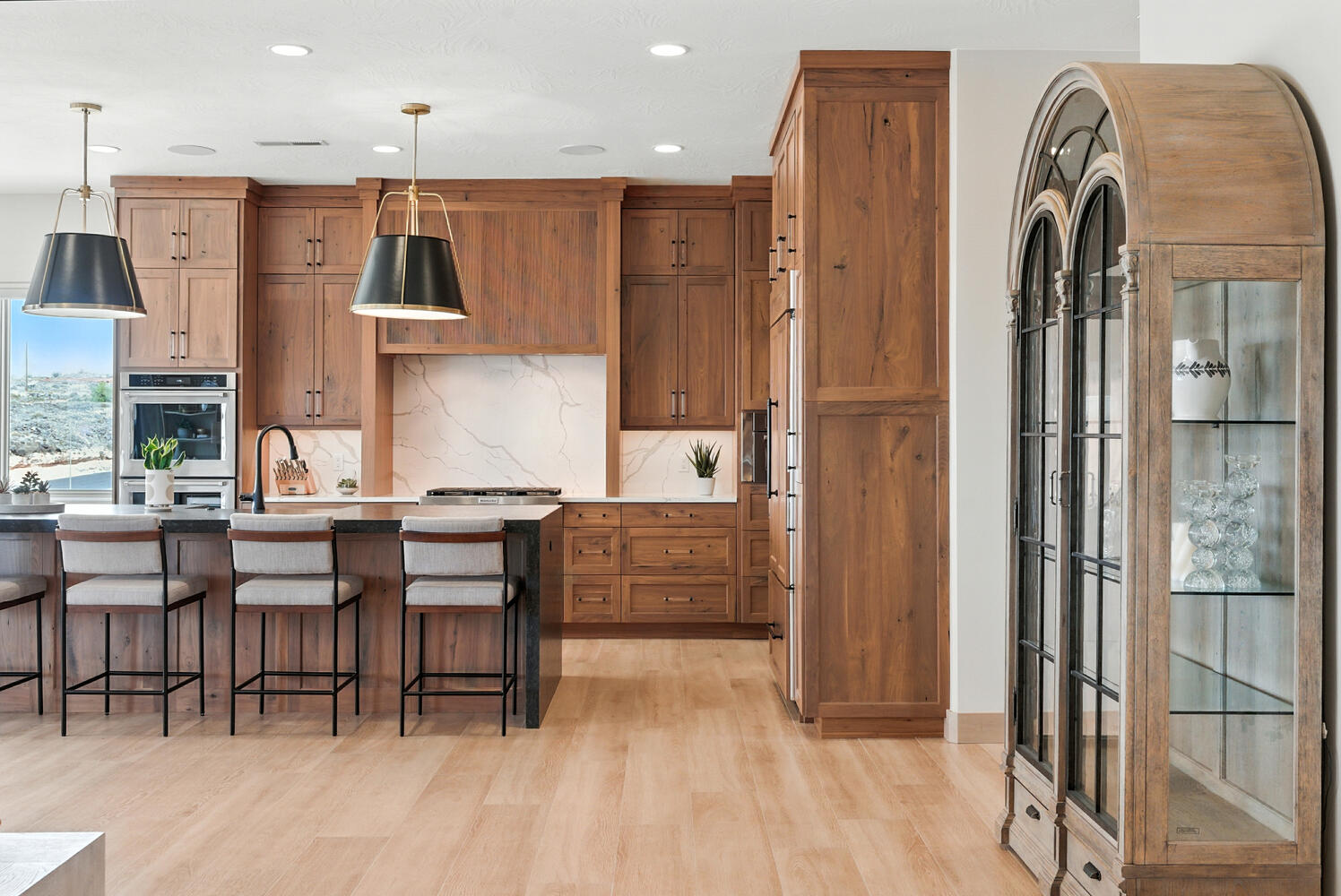 Kitchen featuring brown cabinetry, a kitchen breakfast bar, pendant lighting, backsplash, and light wood-type flooring