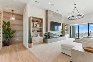 Living room with built in features, light wood-style floors, a chandelier, and recessed lighting