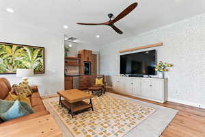 Living area with light wood finished floors, a ceiling fan, recessed lighting, wallpapered walls, and a textured ceiling