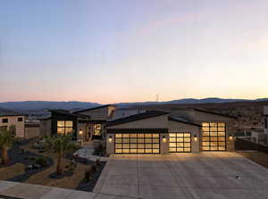 Modern home with an attached garage, driveway, a mountain view, and stucco siding