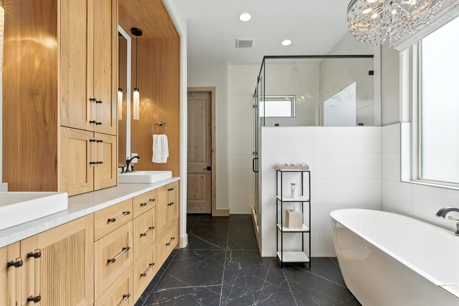 Bathroom featuring a stall shower, a freestanding tub, dark marble finish floors, double vanity, and recessed lighting