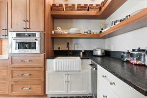 Kitchen featuring dark countertops, open shelves, oven, white cabinetry, and light brown cabinetry