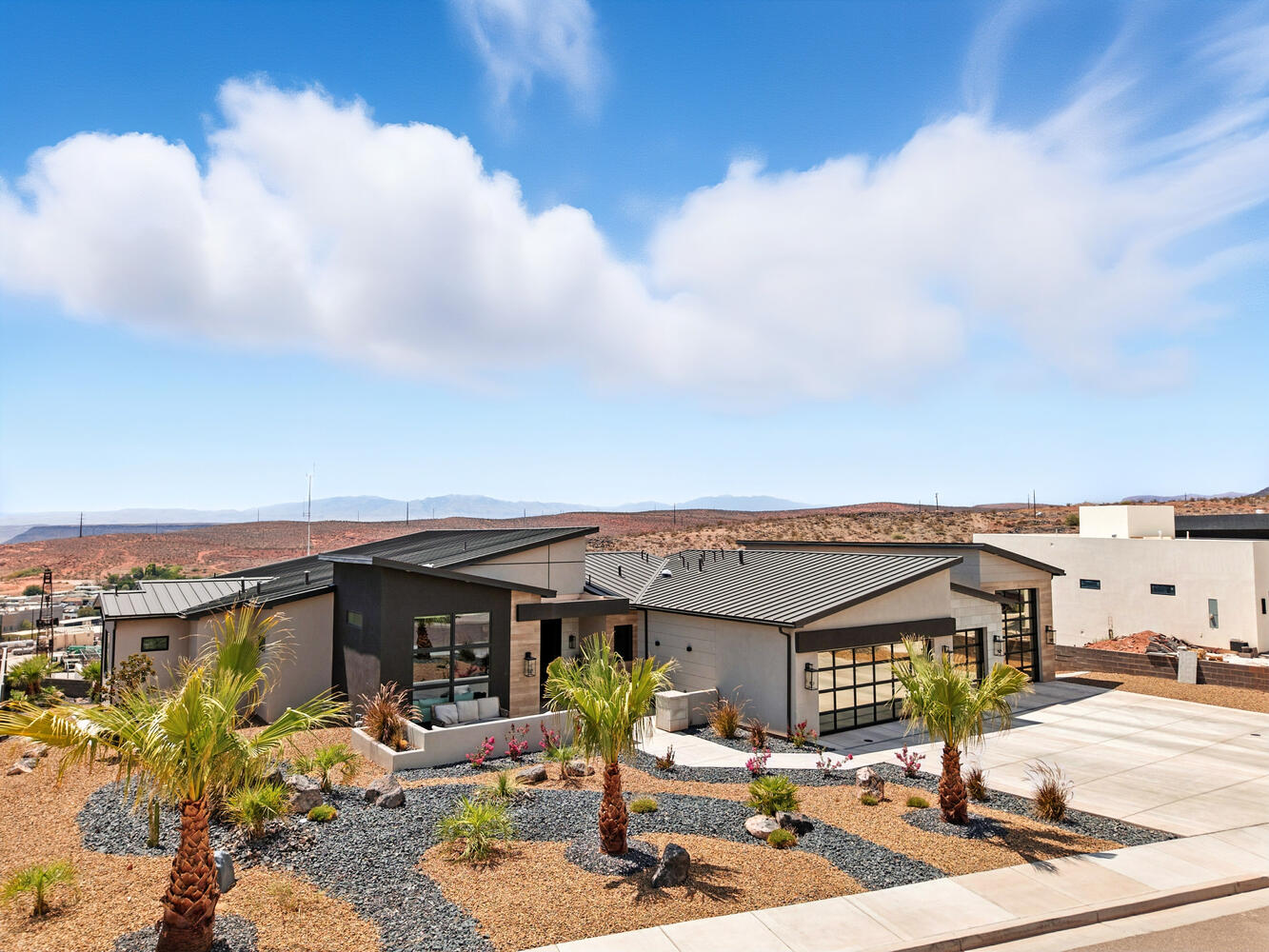 View of front of house with concrete driveway, an attached garage, a standing seam roof, a metal roof, and stucco siding