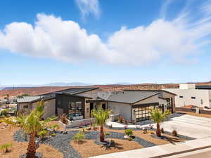 View of front of house with concrete driveway, an attached garage, a standing seam roof, a metal roof, and stucco siding