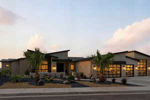 Contemporary home featuring a garage, driveway, a standing seam roof, and a metal roof