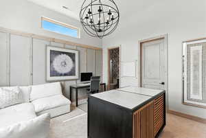 Home office with light colored carpet, a chandelier, and a high ceiling