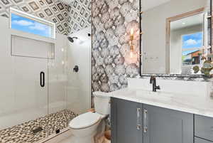 Full bath featuring a stall shower, vanity, plenty of natural light, and wallpapered walls